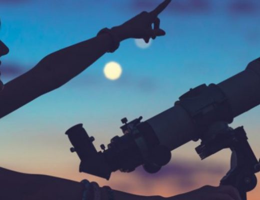 Silhouette of a female student who pointing something towards the black starry sky with a telescope.